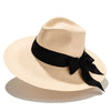 A beige wide-brimmed hat with a black ribbon around the crown, made from handwoven buntal straw with cotton grosgrain trim.